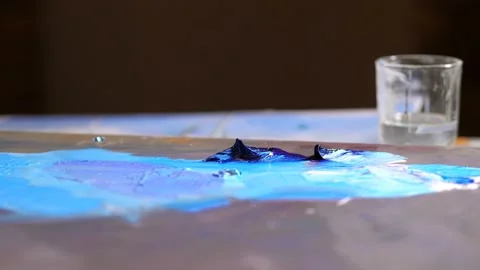 Close-up. Palette with blue paint. A brush appears, picks up blue paint and Video stock 106062553