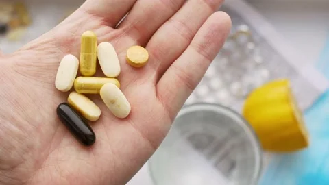 Close-up of a palm squeezing a large number of medicines, pills of various Stock Footage 168128911