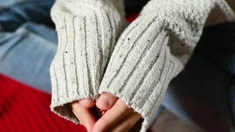 Close-up of the palms half-covered by the sleeves of a knitted sweater holding a Stock Footage 168387557