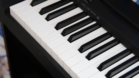 Close up pan across the black and white keys of an electronic keyboard piano Stock Footage 271676051