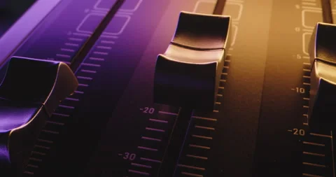 Close up pan across faders of audio mixer at party in flickering colorful light Stock Footage 227007358