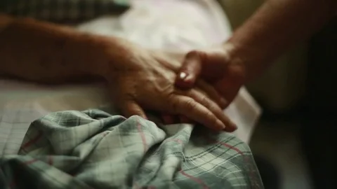 Close Pan of Elderly person holding hands to the bed where she is lying down Video stock 83019781