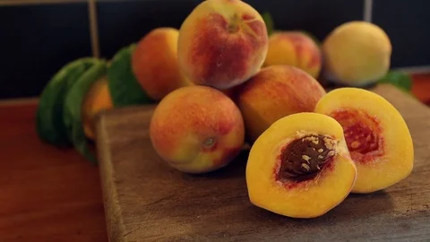 Close up pan of fresh sliced peach and peaches on a rustic timber chopping board Stock Footage 124182798