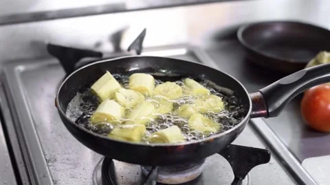 Close-up pan of a frying pan containing pieces of male plantain being fried.. Stock Footage 252098923
