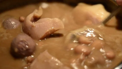 Close up on a pan full of boiled beans with pork, pork rind and salami. Cooking Stock Footage 104774342