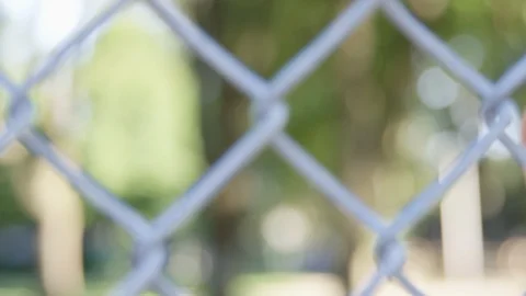 Close Up - Pan to Indian man staring longingly through a chain fence - Slow Stock Footage 125093464
