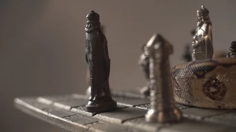 Close up pan of iron chess board with figures and a snake on top. Super Stock Footage 101865792