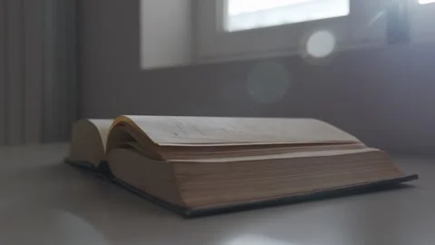 Close Up Pan of Open Book on Table with Lens Flare Stockbeeldmateriaal 334877017