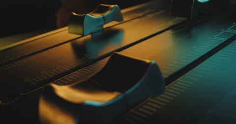 Close-up pan over individual faders of audio mixer in colorful pulsating light Stock Footage 226995570