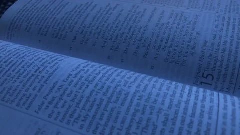 Close-up Pan Over Open Bible in Dimly Lit Room Vídeo Stock 100696687