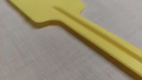 Close-up pan over a yellow plastic kitchen spatula Vídeos de archivo 336460607