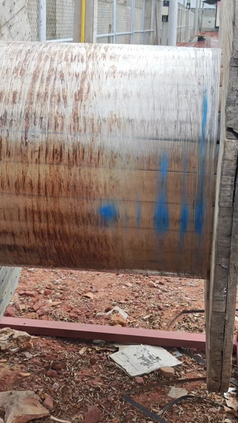 Close up pan right video of empty wooden cable reel drum on metal stand at dirt Stock Footage 338017443
