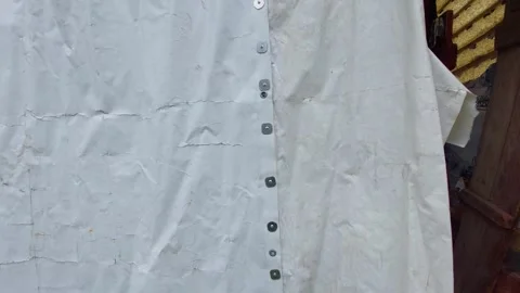 Close-up pan shot of a white heavy-duty waterproof tarpaulin cover fixed with sc Stock Footage 337053511