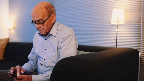 Close up panning shot of elderly man looking at the screen on his mobile phone Stock Footage 99014026