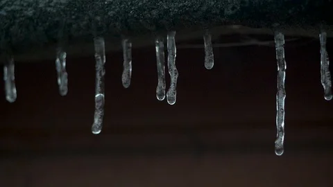 Close up panning shot of lots of icicles hanging from a garden shed Stock Footage 102412910