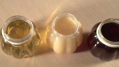 Close up panning to three plastic jars of some kinds honey without caps Stock Footage 220482541