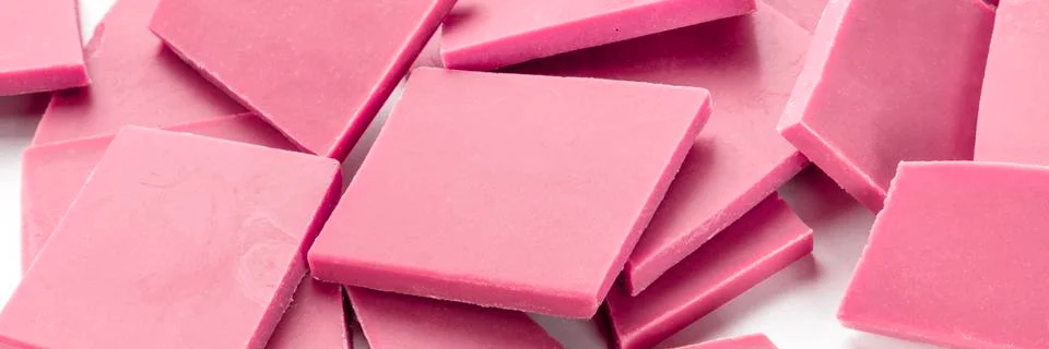 A close-up panorama of ruby chocolate slices, broken on a white background Stock Photos