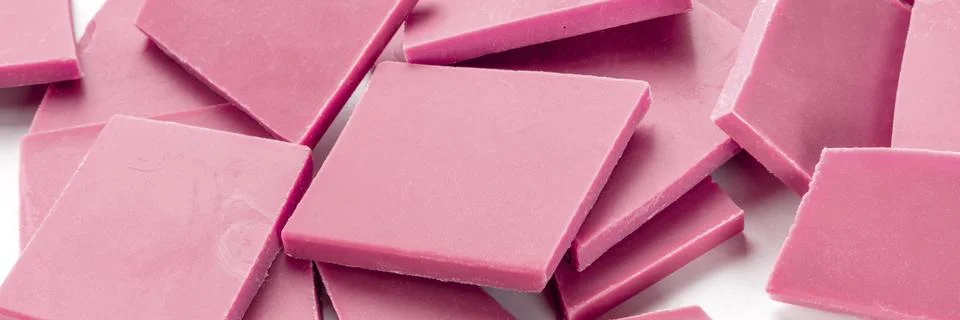 A close-up panorama of ruby chocolate slices, broken on a white background Stock Photos