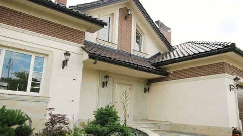 Close up panorama shot of brick modern country house with trees and beds. View Stock Footage 78236530
