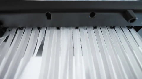 A close up of a paper shredder cutting a sheet of paper into thin strips Stock Footage 297086739