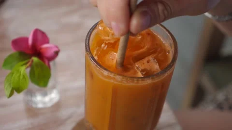 Close up of paper straw stirring fresh carrot juice with ice Stock Footage 146363147
