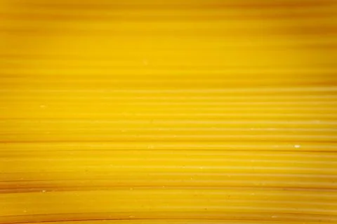 Close-up of parallel strands of yellow uncooked spaghetti. Stock Photos