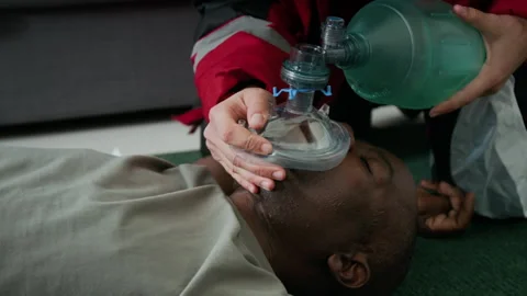 Close-Up of Paramedic Using Bag Valve Mask on Unconscious Man Stock Footage 293676640