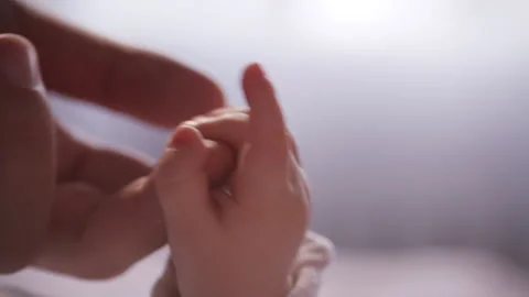 Close Up of Parent Gently Touching Tiny Hand of Newborn Baby Stock Footage 321898865