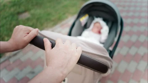 Close up of a parent's hand pushing a stroller handle while walking in a park Vidéo 316642731