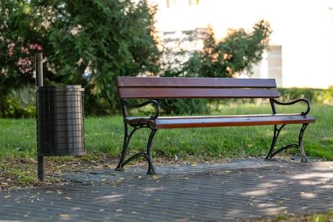 Close up of park bench with trash can in green park surroundings Foto stock
