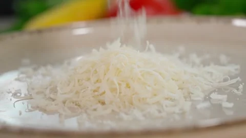 Close-up of Parmesan cheese being grated into a plate on a fine grater. Stock Footage 266317712
