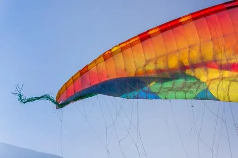 Close-up on part of the wing of a multi-colored paraglider against a blue sky Stock Photos