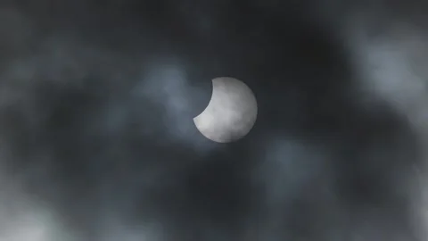 Close up of partial lunar eclipse with dark clouds floating past in the Stock Footage 221319320