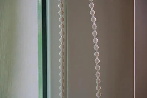 Close-up of partially open window blinds with thin slats and spherical bead d Foto stock