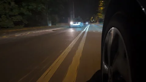 Close-up of a passenger car tire driving on a wet, slippery autumn road surface Stock Footage 287976560