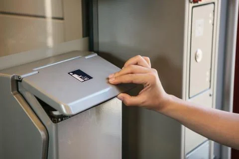 Close-up on the passenger's hand throwing garbage from a special garbage can in Stock Photos