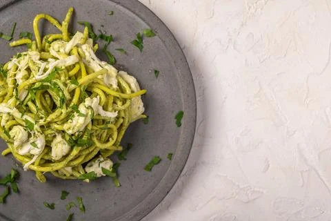 Close up pasta with pesto, stracciatella cheese and parsley served on gray Stock Photos