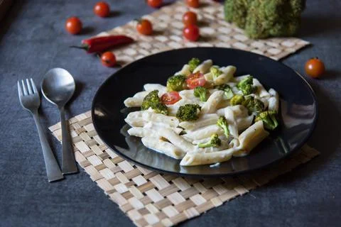 Close up of pasta with spinach, broccoli, cherry tomatoes and cheese in a plate Stock Photos