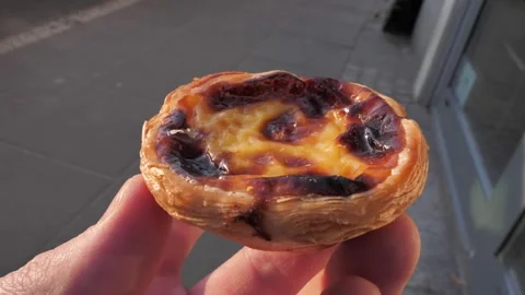 Close-up of pastel de nata cake face against portuguese street Stock Footage 305603732