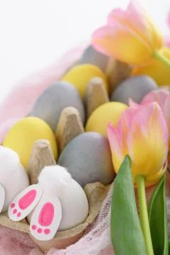 Close-up of pastel Easter eggs with pink tulips, Easter Bunny on pink fabric  Stock Photos