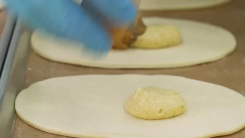 Close-up of Pastry Chef Adding Fruit Filling to Homemade Hand Pie Dough on Bakin Stock Footage 337751383