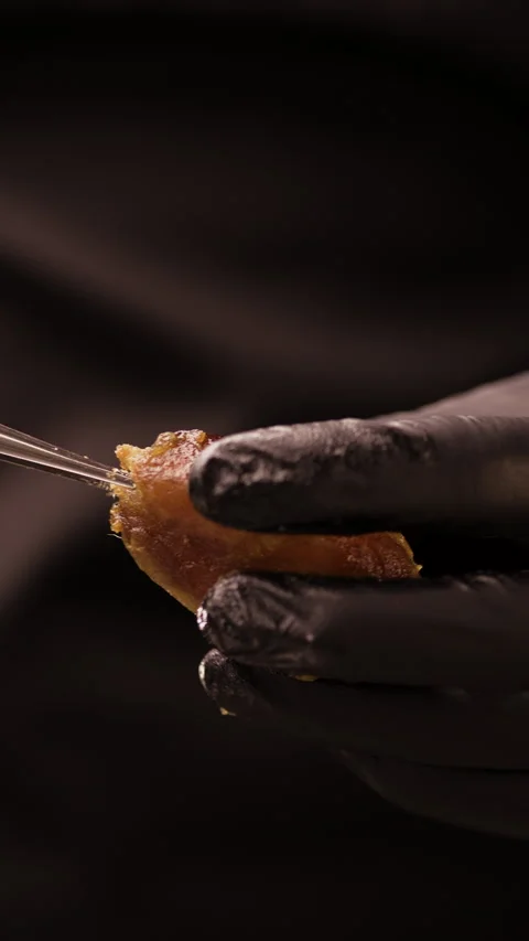Close-up of a pastry chef in black peacock hat removing a pit from a ripe dried Stock Footage 307015936