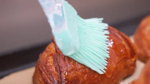 Close-up of Pastry Chef Brushing Liquid Glaze on Golden Flaky Pastry with Silico Stock Footage 337751416