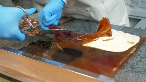 Close-up of a pastry chef in gloves slicing caramel mass with scissors. Stock Footage 330522549