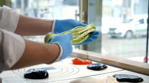 Close-up of a pastry chef mixing colored caramel with his own hands. Stock Footage 256073396