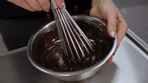 Close-up of a pastry chef mixing liquid chocolate with a whisk in the kitchen. Stock Footage 136834341