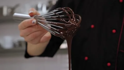 Close-up of a pastry chef mixing liquid chocolate with a whisk in the kitchen. Stock Footage 136845973