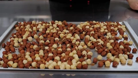 Close-up of pastry chef pouring a lot of hazelnuts on a metal table, slow motion Stock Footage 136845946