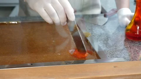 A close-up of a pastry chef pours dye on liquid caramel in a pastry shop. Stock Footage 331696712
