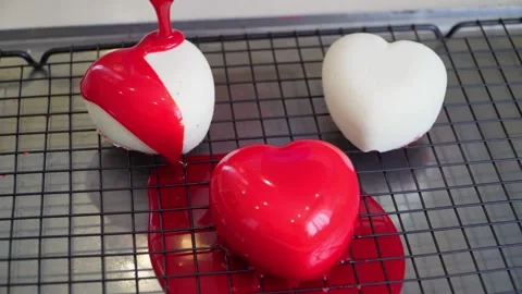Close-up of a pastry chef preparing heart-shaped mousse cakes with red icing. Stock Footage 236083371